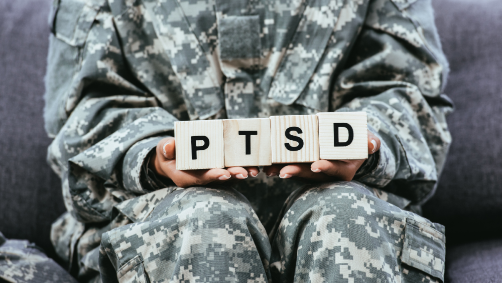 person in military uniform holding blocks that spell ptsd